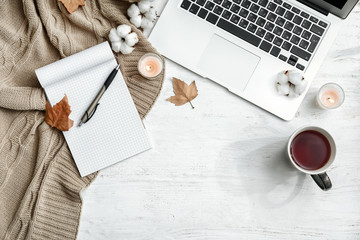 A cozy desk with a notebook, laptop, and tea